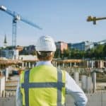 A construction manager looks out on an empty jobsite because workers have gone out for lunch. To avoid potential delays, a workforce catering company should be called on to provide meals on site so workers wouldn't have to leave and risk being late getting back.
